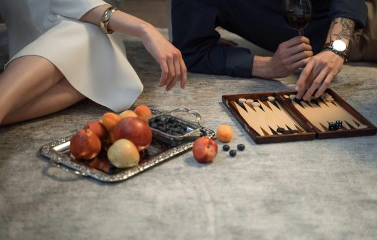 giovane coppia che fa aperitivo e gioca a backgammon su tappeto moderno artorient