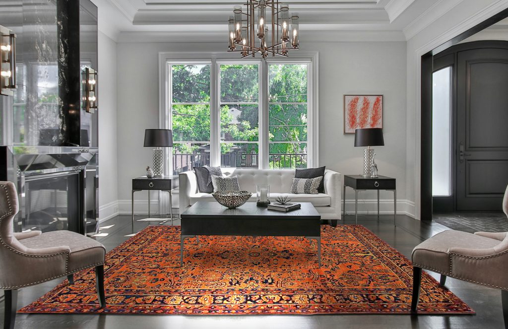 tappeto persiano antico color arancione in soggiorno neoclassico moderno bianco, sotto un tavolino nero e con due consolle ai lati