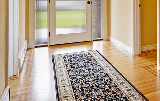 House interior. Entrance hallway with glass door, hardwood floor and rug. View of piano