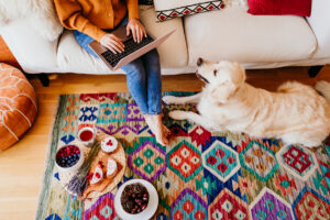 tappeto kilim sotto divano moderno bianco con donna che lavora al laptop e cane